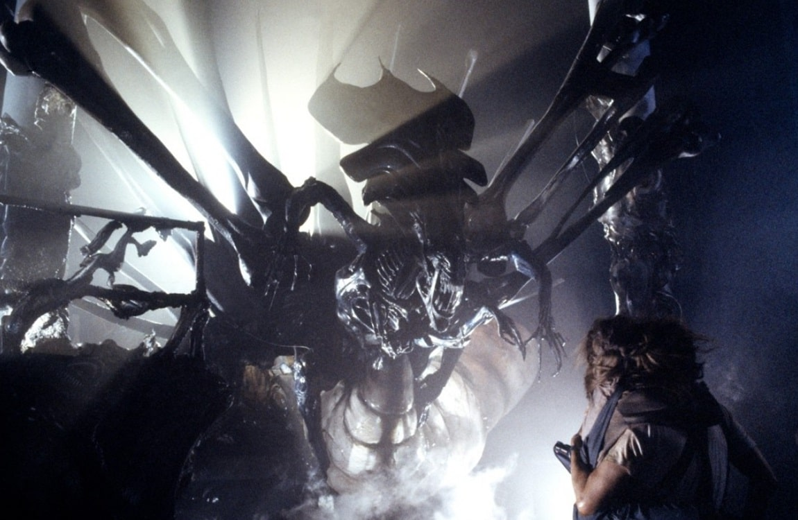 The Alien Queen looms over Ripley in the industrial hive